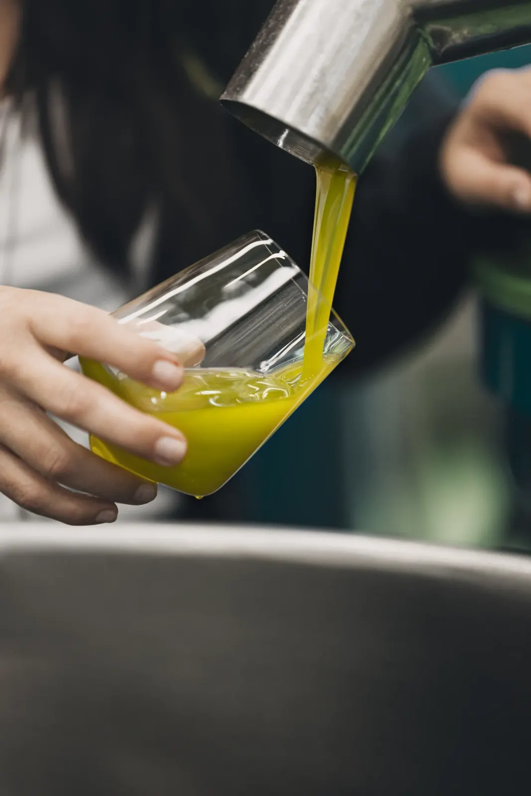 Olio nuovo che cola dal frantoio in un bicchiere