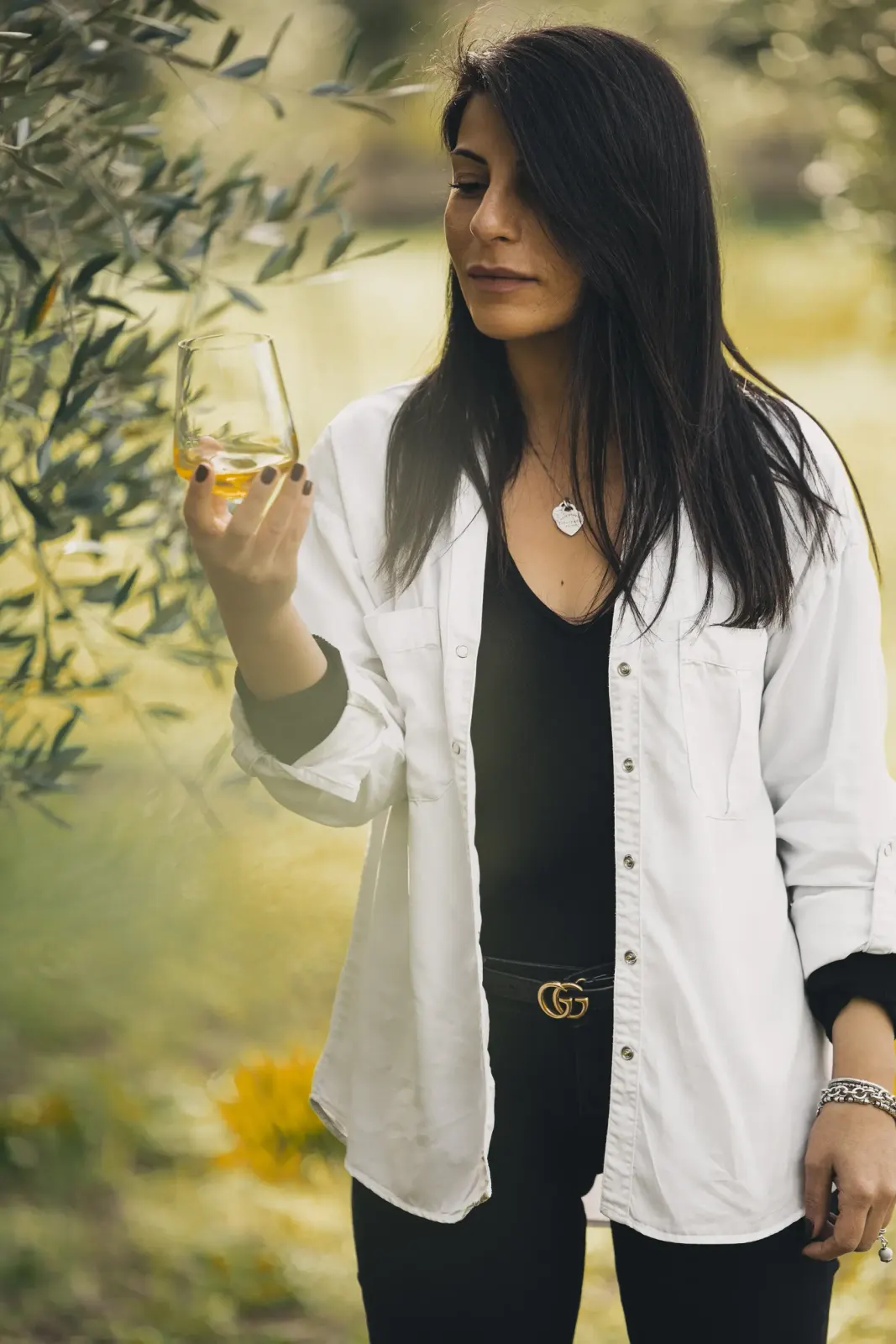 Una donna assaggia l'olio appena estratto, in mezzo all'uliveto