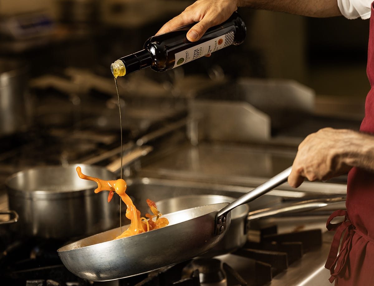 Olio extravergine versato in padella durante la cottura.