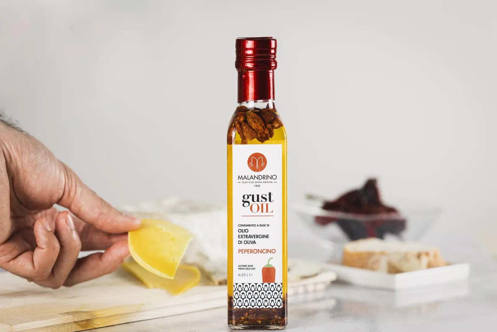 Gust'Oil al peperoncino in tavola, accanto a formaggi e pane
